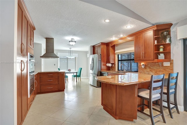 10967 NW 12th Dr, Coral Springs, FL 33071 - kitchen with a peninsula, stainless steel appliances, exhaust hood, brown cabinetry, and decorative backsplash