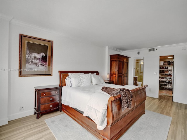 1470 NE 123rd St Unit Aph9, North Miami, FL 33161 - bedroom featuring light wood-style flooring, crown molding, a spacious closet, ensuite bathroom, and a closet