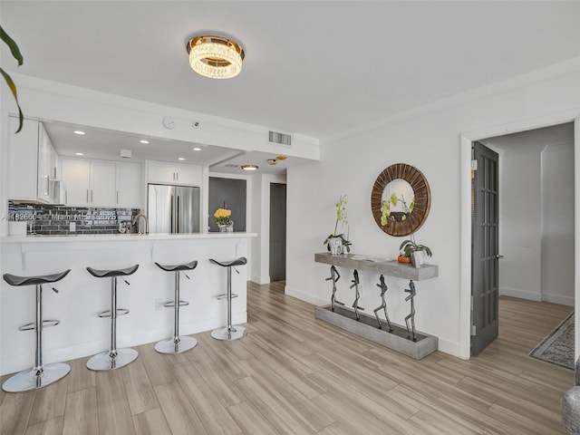 1470 NE 123rd St Unit Aph9, North Miami, FL 33161 - kitchen with high quality fridge, a breakfast bar, light wood-style floors, and backsplash