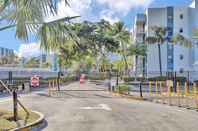 1470 NE 123rd St Unit Aph9, North Miami, FL 33161 - view of asphalt road featuring a gated entry, curbs, traffic signs, and a gate