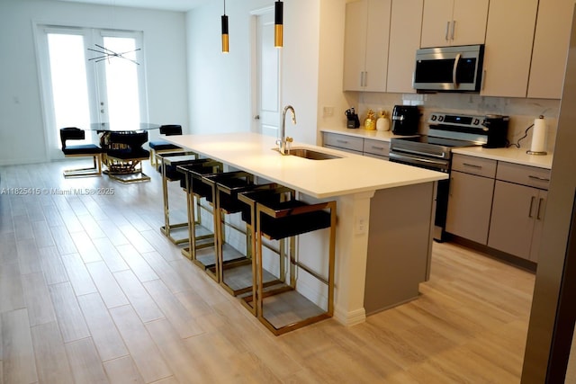 2375 Lancashire St, Davenport, FL 33896 - kitchen featuring appliances with stainless steel finishes, light wood finished floors, a breakfast bar area, an island with sink, and light countertops
