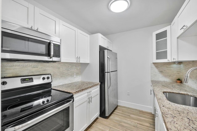8261 SW 128th St Unit 215, Pinecrest, FL 33156 - kitchen with appliances with stainless steel finishes, white cabinets, light wood-style floors, and decorative backsplash