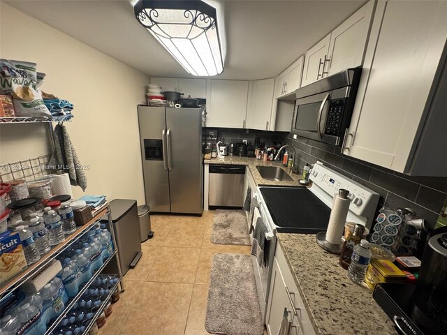 1428 SE 4th Ave Unit 103, Deerfield Beach, FL 33441 - kitchen with stainless steel appliances, white cabinetry, backsplash, light tile patterned floors, and light stone counters