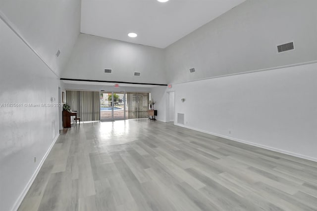 1428 SE 4th Ave Unit 103, Deerfield Beach, FL 33441 - unfurnished living room featuring a towering ceiling and light wood-style floors
