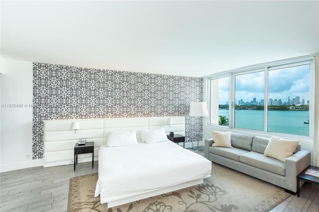 1100 W Ave Unit 506, Miami Beach, FL 33139 - bedroom with wood finished floors, wallpapered walls, a view of skyline, a water view, and an accent wall