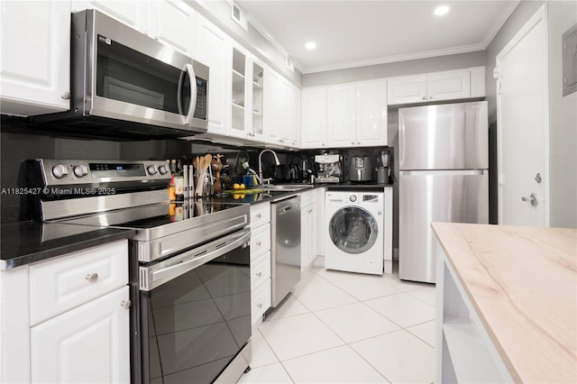 6770 Indian Creek Dr Unit 14C, Miami Beach, FL 33141 - kitchen featuring appliances with stainless steel finishes, washer / dryer, crown molding, white cabinets, and glass insert cabinets