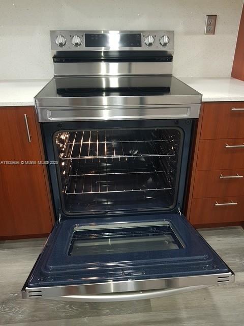 10288 NW 9th St Cir Unit 306, Miami, FL 33172 - kitchen view of stainless steel range with electric stovetop, brown cabinets, and light countertops