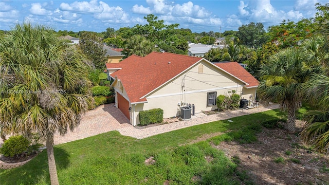 1381 SW Leisure Ln, Port St Lucie, FL 34953 - back of house featuring an attached garage, stucco siding, driveway, a lawn, and a shingled roof