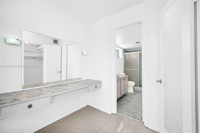 3551 NE 169th St Unit 312, North Miami Beach, FL 33160 - bathroom with a shower stall, tile patterned flooring, vanity, a walk in closet, and a textured ceiling