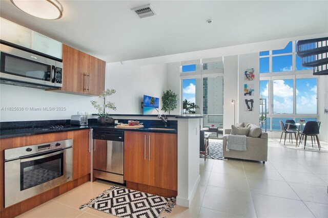 300 S Biscayne Blvd Unit L-1228, Miami, FL 33131 - kitchen featuring appliances with stainless steel finishes, brown cabinetry, a peninsula, dark countertops, and open floor plan