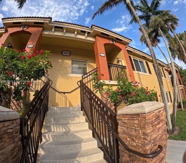 985 NE 34th Ave Unit 203, Homestead, FL 33033 - view of front of house featuring stucco siding, stairs, and a tile roof