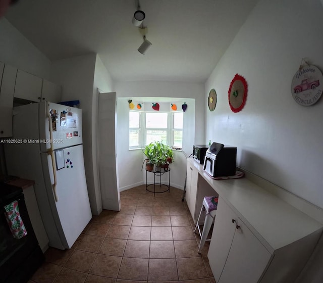 985 NE 34th Ave Unit 203, Homestead, FL 33033 - kitchen featuring freestanding refrigerator, an office area, white cabinets, and tile patterned flooring