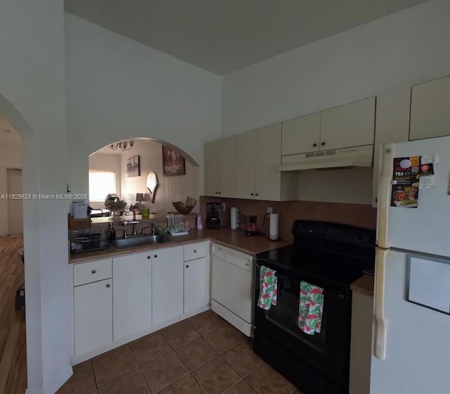 985 NE 34th Ave Unit 203, Homestead, FL 33033 - kitchen with white appliances, under cabinet range hood, arched walkways, white cabinetry, and a high ceiling