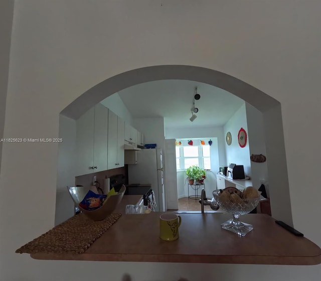 985 NE 34th Ave Unit 203, Homestead, FL 33033 - kitchen featuring arched walkways, range with electric cooktop, under cabinet range hood, and rail lighting