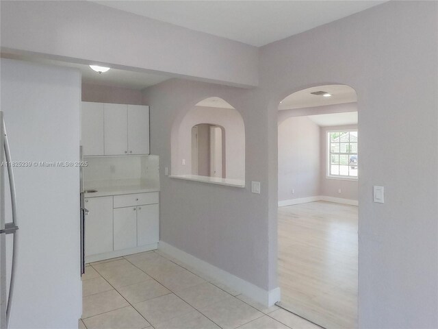 1051 NW 63rd St, Miami, FL 33150 - kitchen with white cabinetry, light countertops, arched walkways, and light tile patterned floors