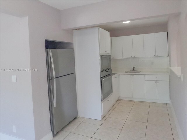 1051 NW 63rd St, Miami, FL 33150 - kitchen featuring appliances with stainless steel finishes, light countertops, white cabinetry, and light tile patterned floors