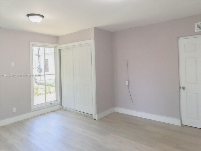 1051 NW 63rd St, Miami, FL 33150 - unfurnished bedroom featuring light wood-style flooring, multiple windows, and a closet