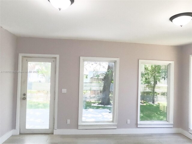 1051 NW 63rd St, Miami, FL 33150 - doorway to outside featuring baseboards and light wood-style flooring