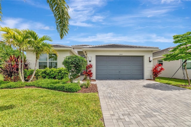 13307 SW Green Delta Rd, Port St Lucie, FL 34987 - view of front facade with decorative driveway, an attached garage, a front yard, and stucco siding