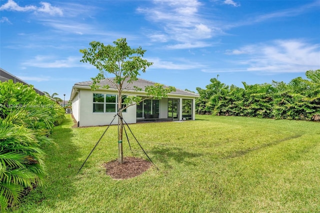 13307 SW Green Delta Rd, Port St Lucie, FL 34987 - back of property featuring stucco siding, a lawn, a sunroom, and a tiled roof