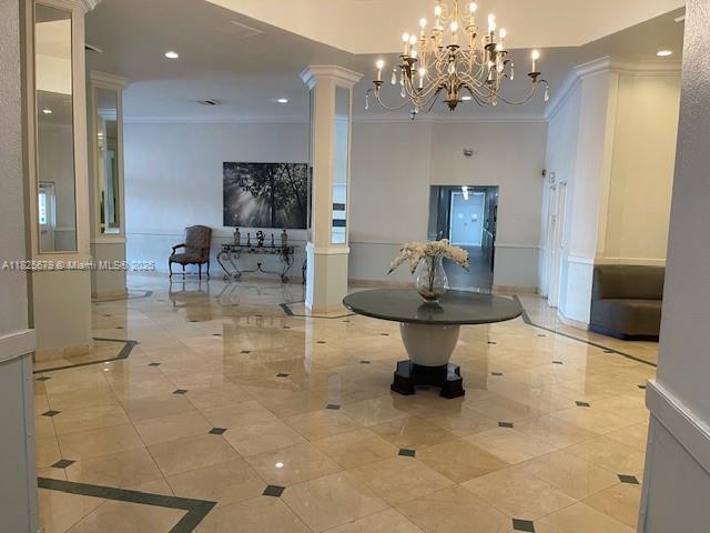1351 NE Miami Gardens Dr Unit 1014E, Miami, FL 33179 - hall with crown molding, decorative columns, light tile patterned flooring, recessed lighting, and a chandelier