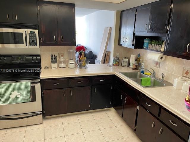 1351 NE Miami Gardens Dr Unit 1014E, Miami, FL 33179 - kitchen featuring electric range, stainless steel microwave, tasteful backsplash, and light tile patterned flooring