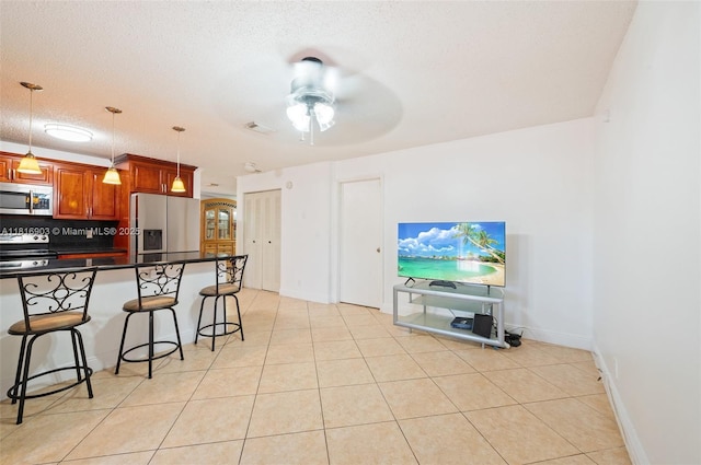 4333 SW 84th Ter, Davie, FL 33328 - kitchen with stainless steel appliances, dark countertops, a breakfast bar, ceiling fan, and pendant lighting