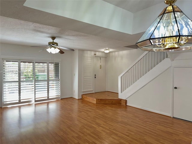 1143 NW 122nd Ter, Pembroke Pines, FL 33026 - unfurnished living room featuring wood finished floors, stairway, a ceiling fan, a chandelier, and a textured ceiling