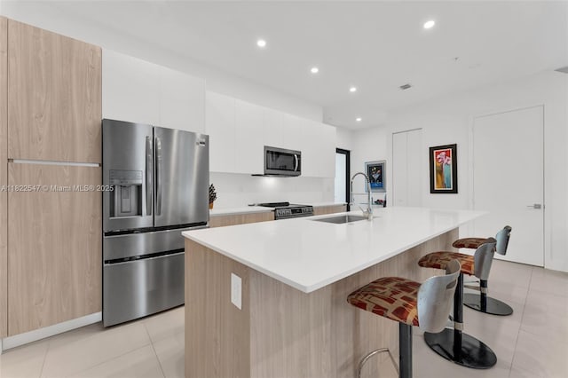 4212 NE 7th Ter, Oakland Park, FL 33334 - kitchen featuring appliances with stainless steel finishes, light tile patterned flooring, a kitchen island with sink, a kitchen bar, and modern cabinets
