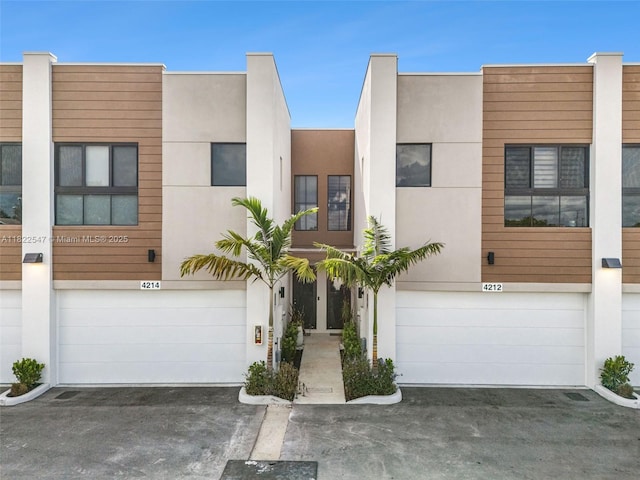 4212 NE 7th Ter, Oakland Park, FL 33334 - view of property with a garage, asphalt driveway, and stucco siding