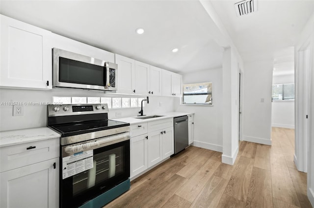 7525 NW 15th Ave, Miami, FL 33147 - kitchen with stainless steel appliances, white cabinetry, light wood-style floors, healthy amount of natural light, and recessed lighting