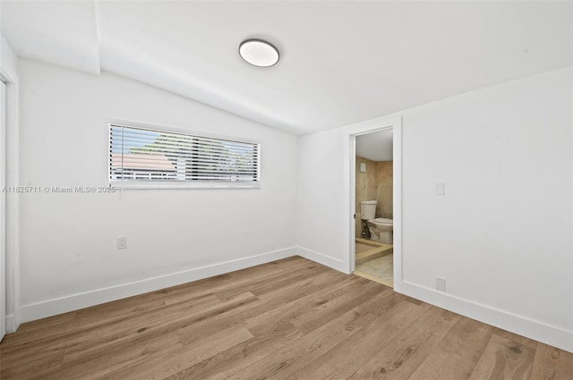 7525 NW 15th Ave, Miami, FL 33147 - unfurnished bedroom featuring lofted ceiling, light wood-style floors, and ensuite bath