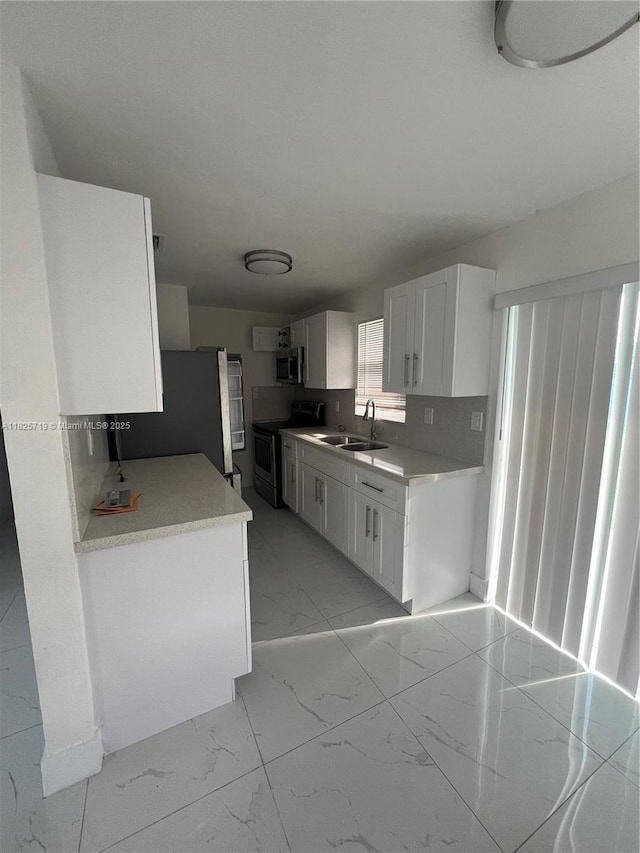 14730 SW 104th Ct, Miami, FL 33176 - kitchen featuring appliances with stainless steel finishes, light marble finish floors, white cabinetry, and light countertops