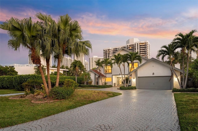 413 Holiday, Hallandale Beach, FL 33009 - view of front facade featuring a garage, stucco siding, decorative driveway, and a lawn