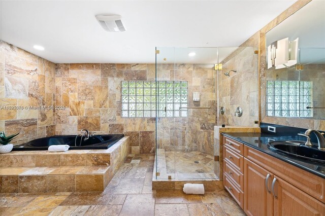 413 Holiday, Hallandale Beach, FL 33009 - bathroom featuring a garden tub, vanity, stone tile floors, a stall shower, and tile walls