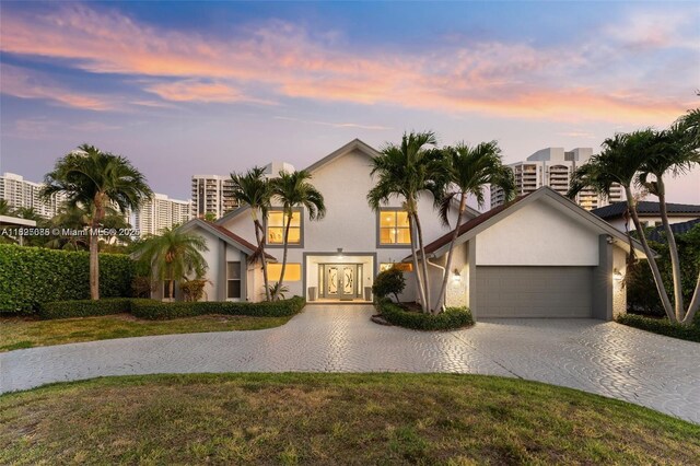 413 Holiday, Hallandale Beach, FL 33009 - view of front of house featuring decorative driveway, a garage, french doors, stucco siding, and a front yard