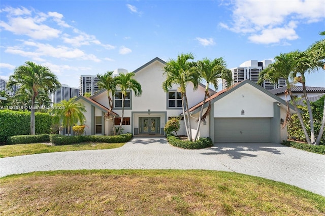 413 Holiday, Hallandale Beach, FL 33009 - view of front facade featuring french doors, decorative driveway, a garage, and stucco siding