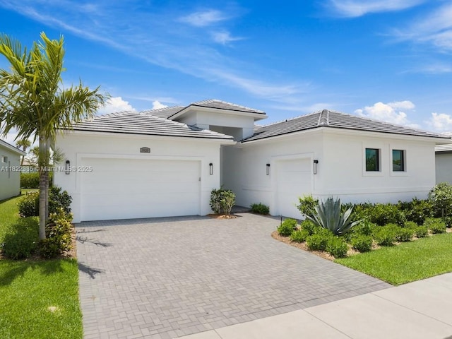 9125 SW Esule Way, Port St Lucie, FL 34987 - prairie-style home with an attached garage, a tile roof, decorative driveway, and stucco siding