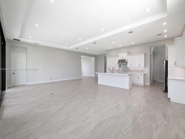 9125 SW Esule Way, Port St Lucie, FL 34987 - unfurnished living room with recessed lighting, a raised ceiling, and light wood-style floors
