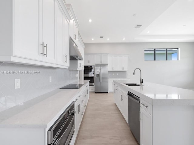 9125 SW Esule Way, Port St Lucie, FL 34987 - kitchen featuring appliances with stainless steel finishes, under cabinet range hood, backsplash, white cabinetry, and recessed lighting
