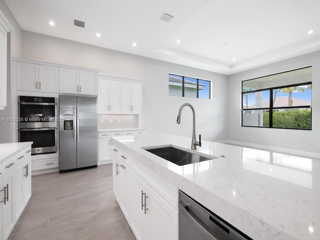 9125 SW Esule Way, Port St Lucie, FL 34987 - kitchen with stainless steel appliances, light stone counters, recessed lighting, white cabinetry, and a tray ceiling