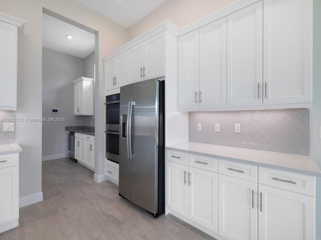 9125 SW Esule Way, Port St Lucie, FL 34987 - kitchen featuring appliances with stainless steel finishes, tasteful backsplash, white cabinets, and light countertops