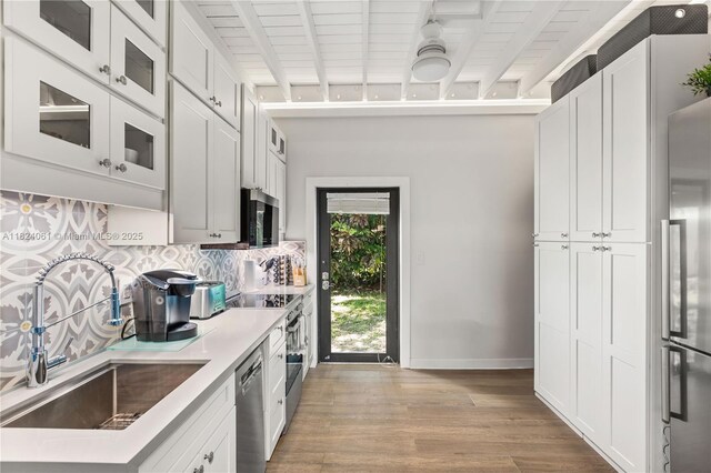 1301 Milan Ave Unit 5, Coral Gables, FL 33134 - kitchen with tasteful backsplash, appliances with stainless steel finishes, light wood-type flooring, white cabinetry, and beamed ceiling