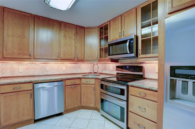 2500 Parkview Dr Unit 405, Hallandale Beach, FL 33009 - kitchen with stainless steel appliances, light stone countertops, decorative backsplash, light tile patterned floors, and glass insert cabinets