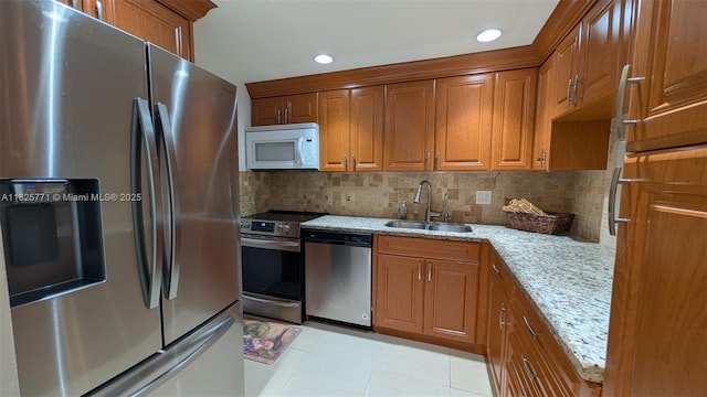 1001 Hillcrest Ct Unit 303, Hollywood, FL 33021 - kitchen with stainless steel appliances, brown cabinets, decorative backsplash, light stone countertops, and light tile patterned floors
