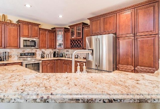 1379 NW 166th Ave, Pembroke Pines, FL 33028 - kitchen with appliances with stainless steel finishes, light stone counters, decorative backsplash, glass insert cabinets, and recessed lighting