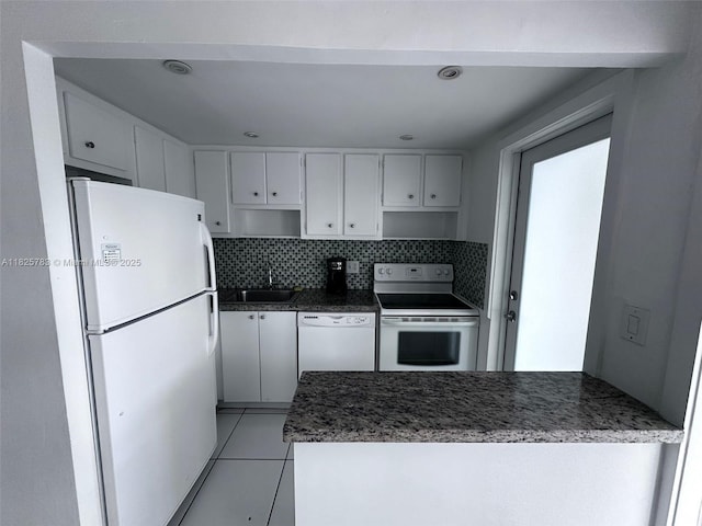 2430 NE 135th St Unit 304, North Miami, FL 33181 - kitchen featuring white appliances, a peninsula, light tile patterned flooring, tasteful backsplash, and dark stone counters