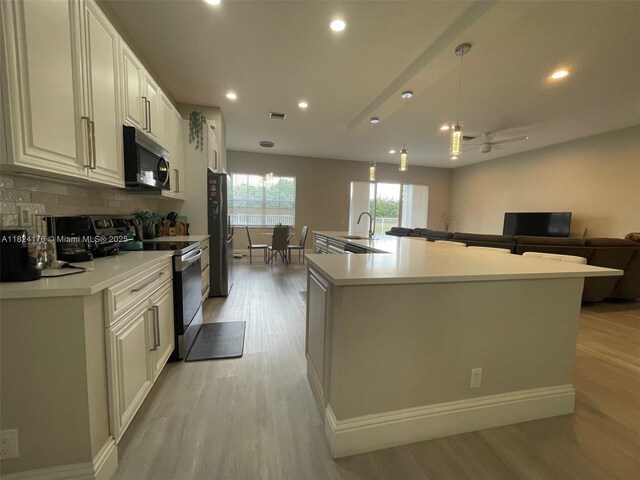 1087 Chenille Cir, Weston, FL 33327 - kitchen with stainless steel appliances, light wood finished floors, a spacious island, recessed lighting, and light countertops