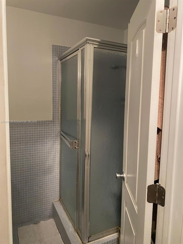 19001 NE 14th Ave Unit 325, Miami, FL 33179 - bathroom featuring a stall shower, tile walls, tile patterned flooring, and a wainscoted wall
