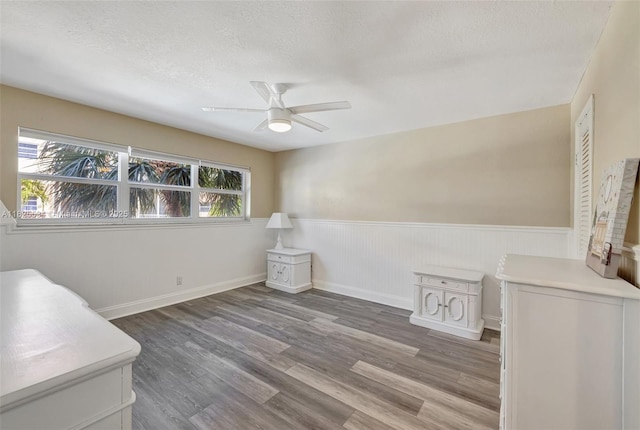 2097 S Ocean Unit 207, Hallandale Beach, FL 33009 - unfurnished bedroom featuring multiple windows, a wainscoted wall, a textured ceiling, wood finished floors, and a ceiling fan